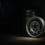 ガレージの隅に置かれたジムニーの純正鉄チンホイール。手前の一つにスポットライトが当たり、これからカスタムされる原石であることを示唆している。